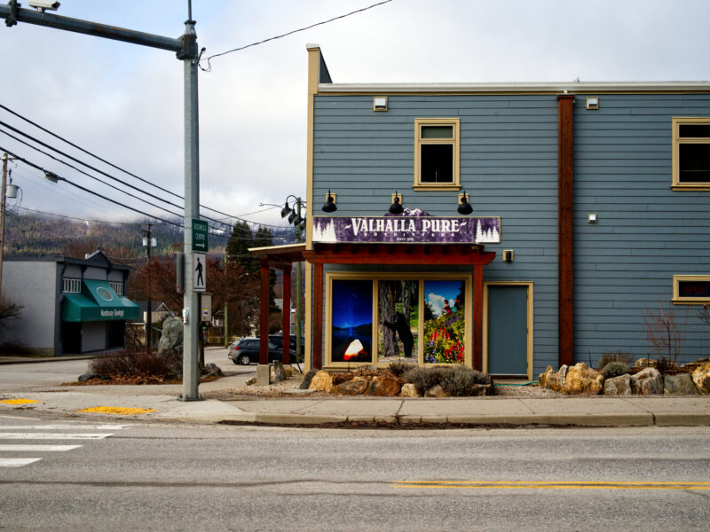 A small outdoor gear store on a street corner with mountains in the background.