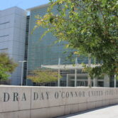 Sandra Day O’Connor U.S. Courthouse exterior with glass building and engraved stone sign in Phoenix, Arizona.