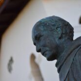 A statue of Junipero Serra in front of a mission building