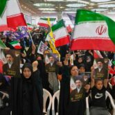 Government supporters wave Iranian flags and hold portraits of Iran’s Supreme Leader during a large indoor ceremony at Imam Khomeini Grand Mosque in Tehran.