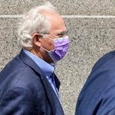Former U.S. Rep. Stephen Buyer, wearing a purple face mask and dark blazer, walks beside his attorney outside a federal courthouse in New York.