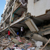 Residents climb over debris and damaged concrete slabs outside a partially collapsed apartment building in Catia La Mar, Venezuela, two days after a series of earthquakes.
