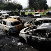 Dozens of burned-out vehicles sit in a damaged car dealership parking lot after two helicopters collided and crashed in Rio de Janeiro.