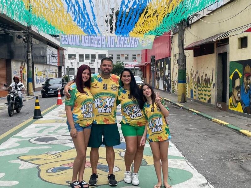 Celso Mendes Jnior stands with his wife and two daughters on a World Cup-painted street covered with green, yellow, blue and white streamers in Rio de Janeiro.