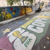 A Rio de Janeiro street features a large World Cup painting with a trophy, the word “Copa,” Brazil’s flag and a mural of a player kissing the cup.