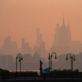 The New York City skyline appears faintly through thick wildfire smoke, viewed from Jersey City across the Hudson River.
