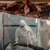 Health workers wearing full protective gear care for an Ebola patient inside a treatment center in eastern Congo.