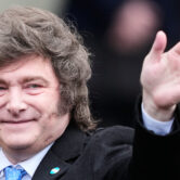 Argentine President Javier Milei smiles and waves while arriving at a cathedral in Buenos Aires.